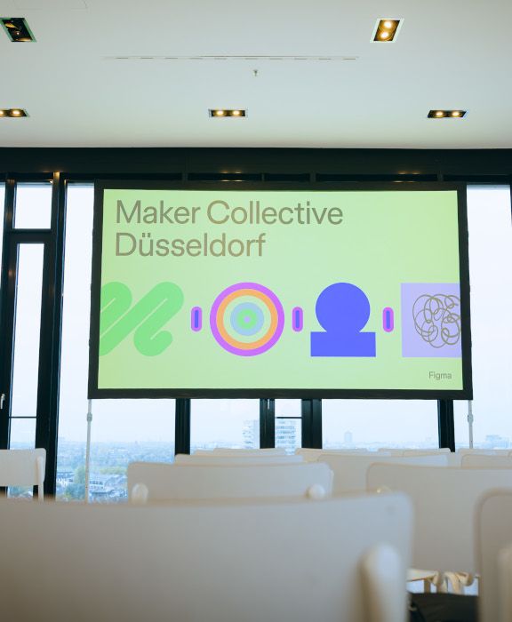 Eventraum mit Blick über Düsseldorf - Bühne des Figma Maker Collective mit bunter Visualisierung und Schriftzug. Präsentation zu UX/UI Design und KI in Figma.